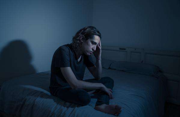 Depressed man sitting on his bed