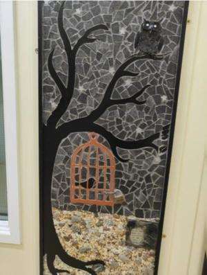 A bird in a cage hanging from a tree